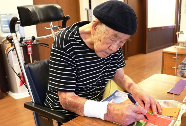  真剣な眼差しでペンを持つ102歳のご入居者様は、ユーモアたっぷりの願いを書いてくださいました。お元気の秘訣です！！  