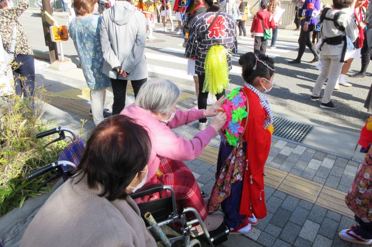 里引きの休憩の最中、華やかな衣装を着た女の子の衣装をご入居者が直してあげている１コマです。