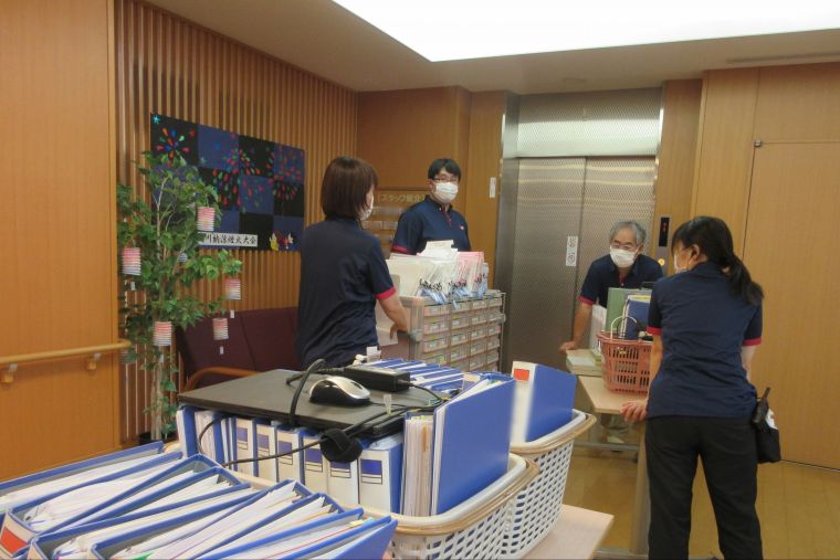 警戒レベル３発令時の物品確保訓練では、１階で管理している薬や連絡手段等の重要物品の他、個人情報の書類等を４階に移動する訓練を行なっています。