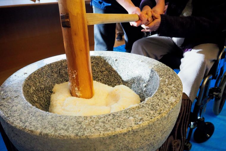 蒸かしたてのもち米をみんなで力を合わせて搗いていきます。車イスの方もスタッフの力を借りながら頑張っていただきました